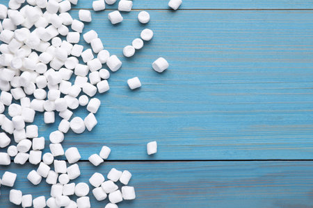 Delicious marshmallows on light blue wooden table, flat lay. Space for text