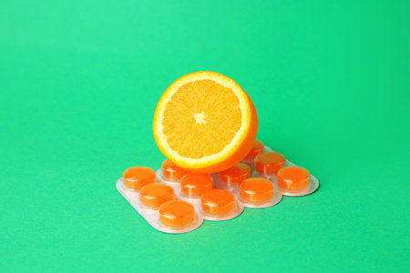 Blister with cough drops and fresh orange on green backgroundの写真素材