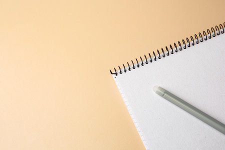 Notepad with erasable pen on beige background, top view. Space for text