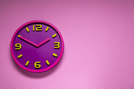 Stylish round clock on pale pink background, top view with space for text. interior element