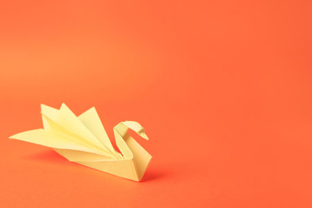origami art. Paper swan on orange background, space for textの写真素材
