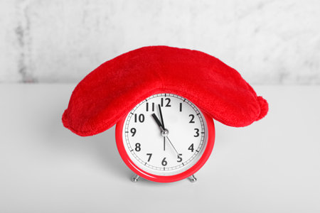 Red sleep mask and alarm clock on white tableの写真素材