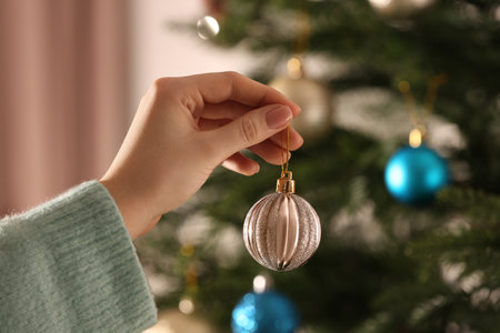 Woman with shiny Christmas ball near tree indoors, closeup. Space for textの写真素材