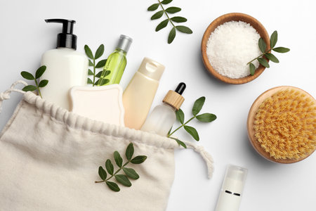 Preparation for spa. Compact toiletry bag, twigs and cosmetic products on white background, flat layの写真素材
