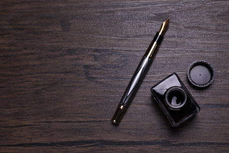 Inkwell and fountain pen on wooden table, flat lay. Space for textの写真素材