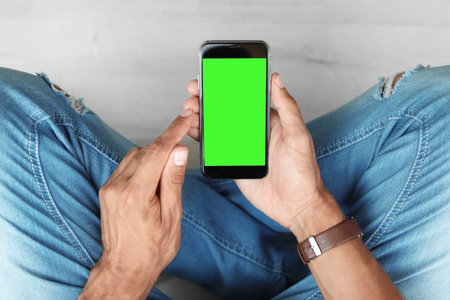 Man using smartphone with green screen, closeup. Gadget display with chroma key. Mockup for designの写真素材