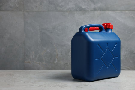 New blue plastic canister on floor near light gray wall, space for text