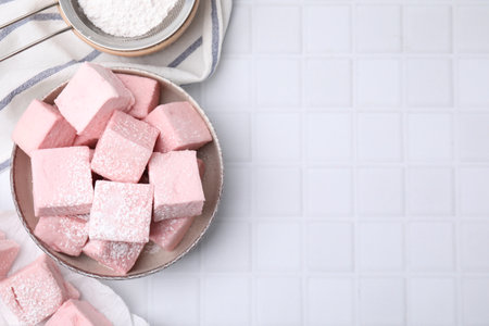 Bowl of delicious sweet marshmallows with powdered sugar on white table, flat lay. Space for textの写真素材