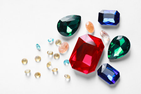 Different beautiful gemstones for jewelry on white background, flat lay