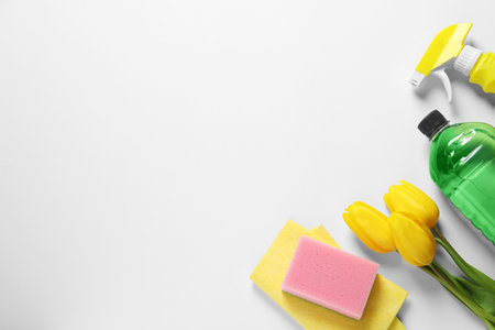 spring cleaning. Detergents, flowers, sponge and rag on white background, flat lay. Space for textの写真素材