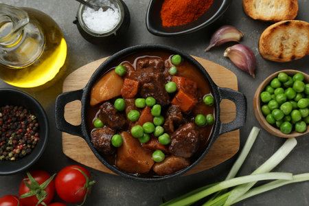 Delicious beef stew and ingredients on gray table, flat layの写真素材