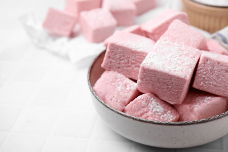 Bowl of delicious sweet marshmallows with powdered sugar on white table, closeup. Space for textの写真素材