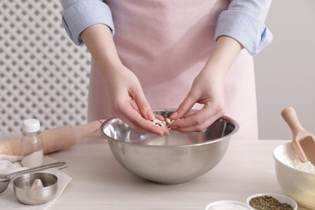 Woman making traditional grissini at white wooden table indoors, closeup