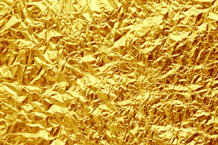 Crumpled golden foil as background, closeup viewの写真素材