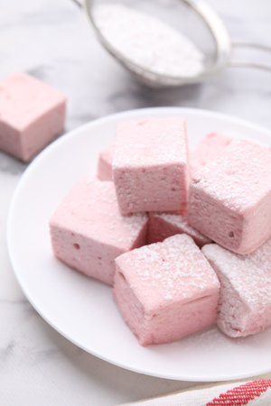 Plate of delicious sweet marshmallows with powdered sugar on white marble tableの写真素材