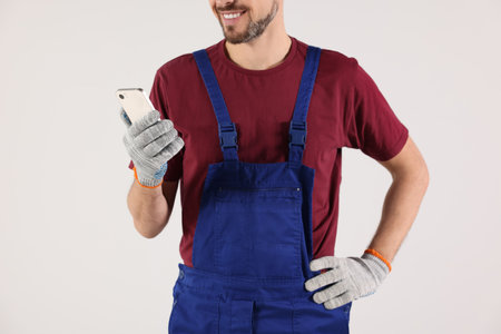 Professional repairman in uniform with phone indoors, closeupの写真素材
