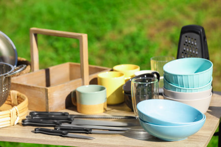 Many different items for kitchen on wooden table outdoors. Garage sale