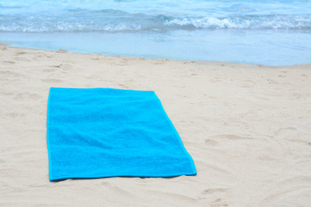 Blue towel on sandy beach near sea, space for textの写真素材