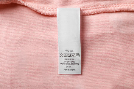 Clothing label on beautiful pink garment, top viewの写真素材