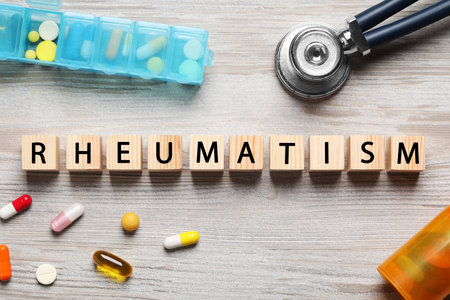 Word Rheumatism made of cubes, stethoscope and pills on wooden table, flat layの写真素材