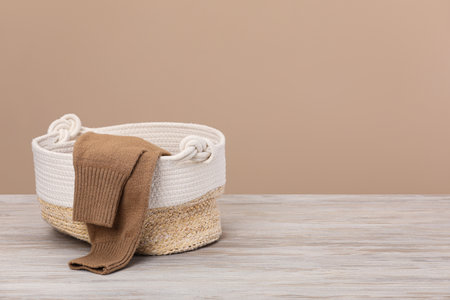 Wicker laundry basket with clothes near beige wall. Space for textの写真素材