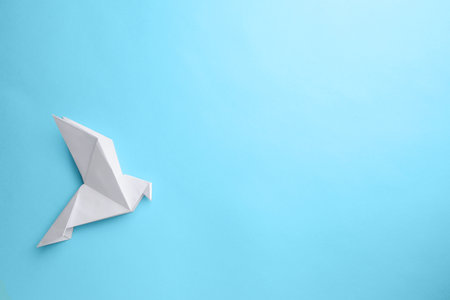 origami art. Beautiful handmade paper bird on light blue background, top view. Space for textの写真素材