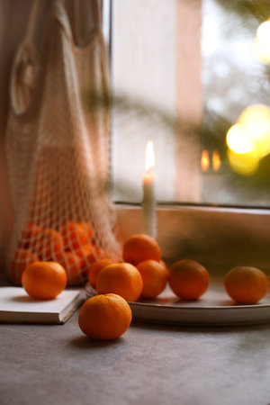 Fresh ripe tangerines and Christmas decor on gray table near windowの写真素材