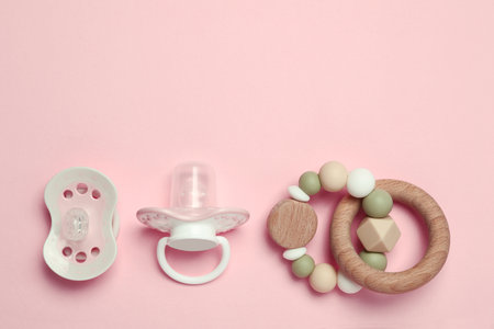 Flat lay composition with pacifiers and other baby stuff on pink background. Space for textの写真素材