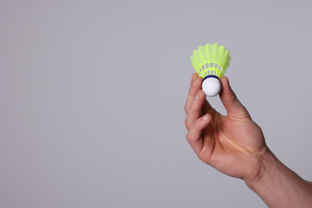 Man with badminton shuttlecock on light gray background, closeup. Space for textの写真素材