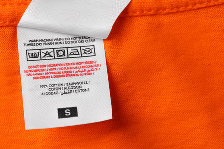 Clothing labels on orange garment, top view. Space for textの写真素材