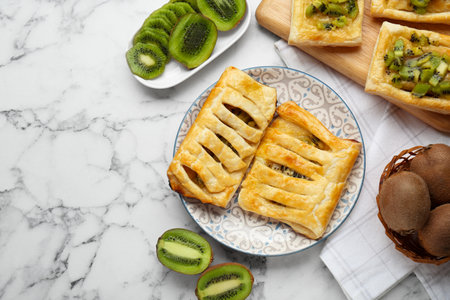 Fresh tasty puff pastry with kiwi on white marble table, flat lay. Space for textの写真素材