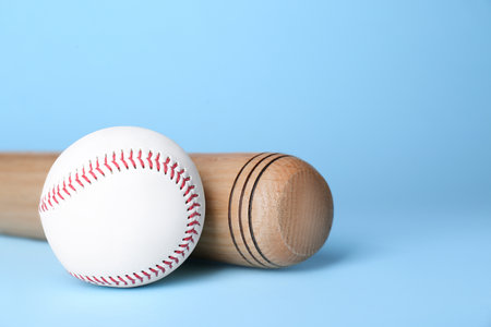 Wooden baseball bat and ball on light blue background, space for text. sports equipmentの写真素材
