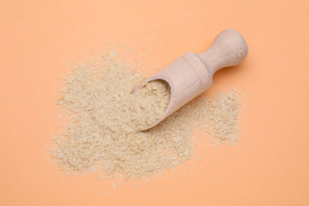 Scoop with beer yeast flakes on pale orange background, top viewの写真素材