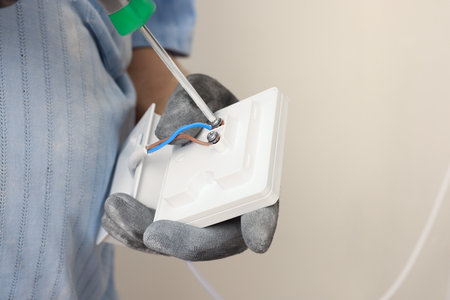 Electrician with screwdriver installing remote meter indoors, closeup