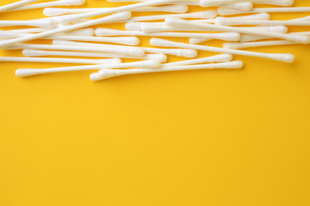 Many clean cotton buds on yellow background, flat lay. Space for textの写真素材