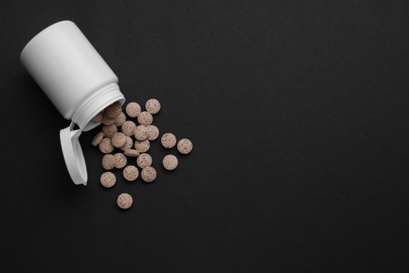 Jar with brewer`s yeast tablets on black background, flat lay. Space for textの写真素材