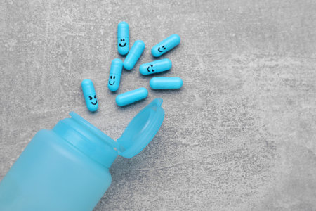 Antidepressants with happy emoticons and medical jar on light gray textured background, flat lay. Space for textの写真素材