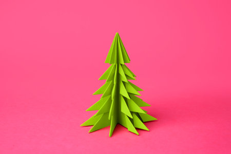 origami art. Handmade paper Christmas tree on pink backgroundの写真素材