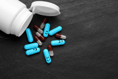 Antidepressants with happy emoticons and medical jar on black background, flat lay. Space for textの写真素材
