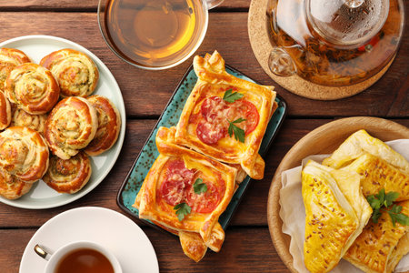 Various delicious puff pastry served with tea on wooden table, flat layの写真素材