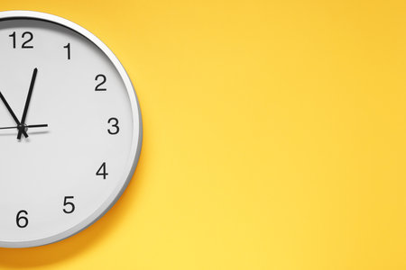 Stylish round clock on yellow background, top view with space for text. Interior elementの写真素材