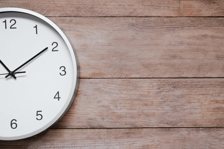 Stylish round clock on wooden table, top view with space for text. interior element