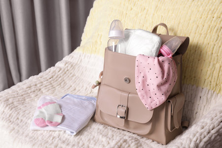 Mother's bag with baby's stuff on armchair indoorsの写真素材