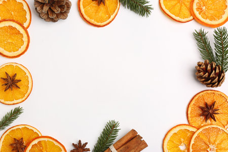 Frame made of dry orange slices, anise stars, fir branches and cones on white background, flat lay. Space for textの写真素材