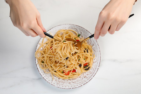 Woman eating delicious pasta at white marble table, top viewの写真素材