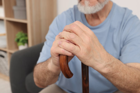 Senior man with walking cane at home, closeupの写真素材