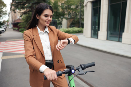 Businesswoman with modern electric kick scooter on city street, space for textの写真素材