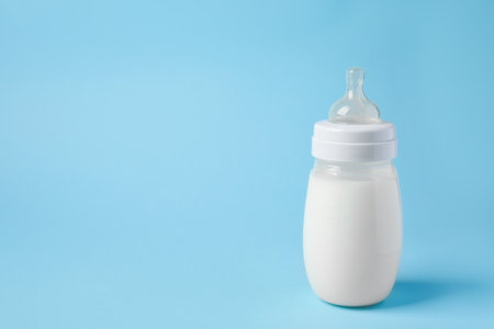 One feeding bottle with milk on light blue background. Space for textの写真素材