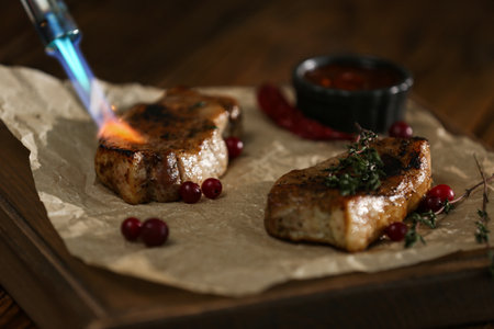 Cooking meat medallions with manual gas burner on wooden table in photo studio, closeup. food stylistの写真素材