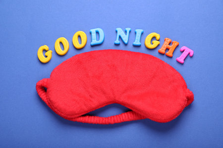 Soft sleep mask and words Good Night made of colorful letters on blue background, flat layの写真素材